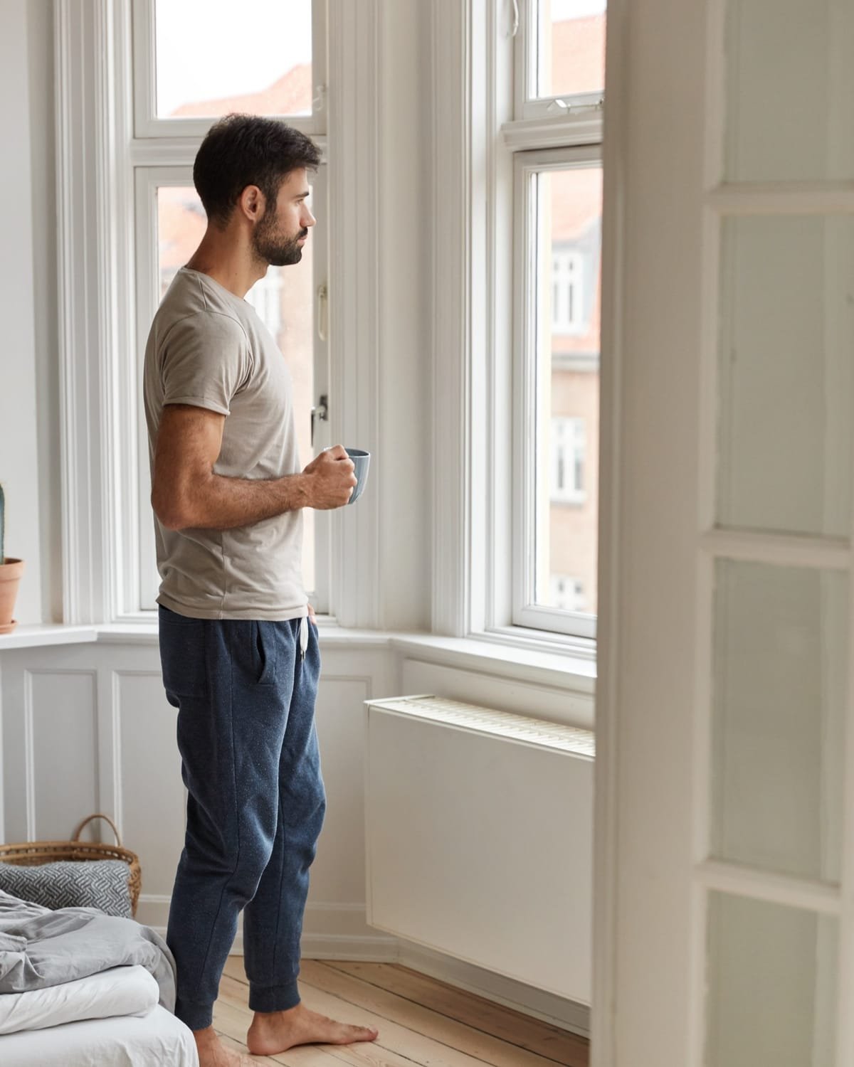 Homme s’étirant avec énergie près de la fenêtre le matin